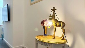 Una lámpara con forma de jirafa sobre una mesa de madera con un jarrón de flores.