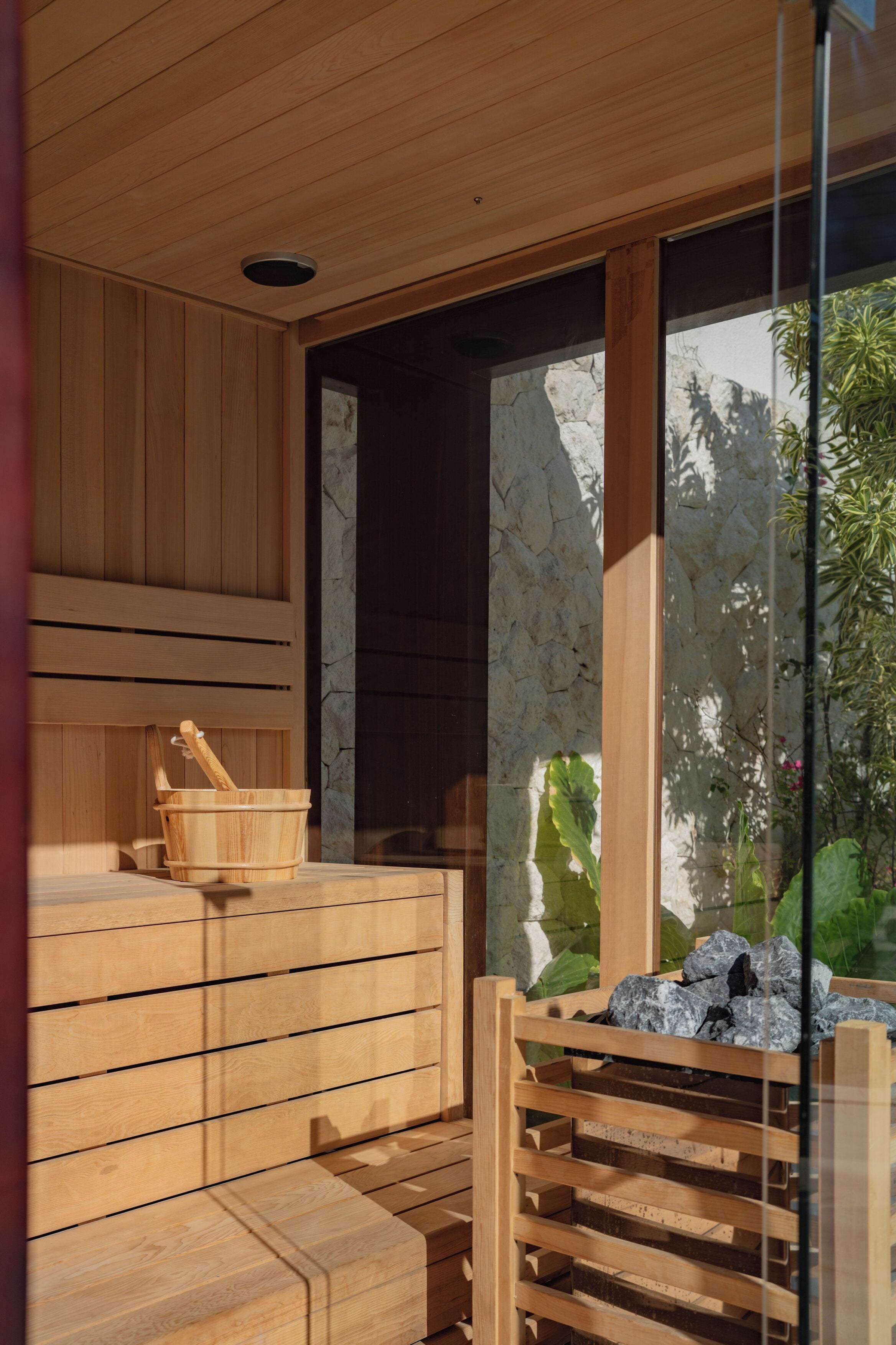 A wooden sauna with benches and a stone wall.