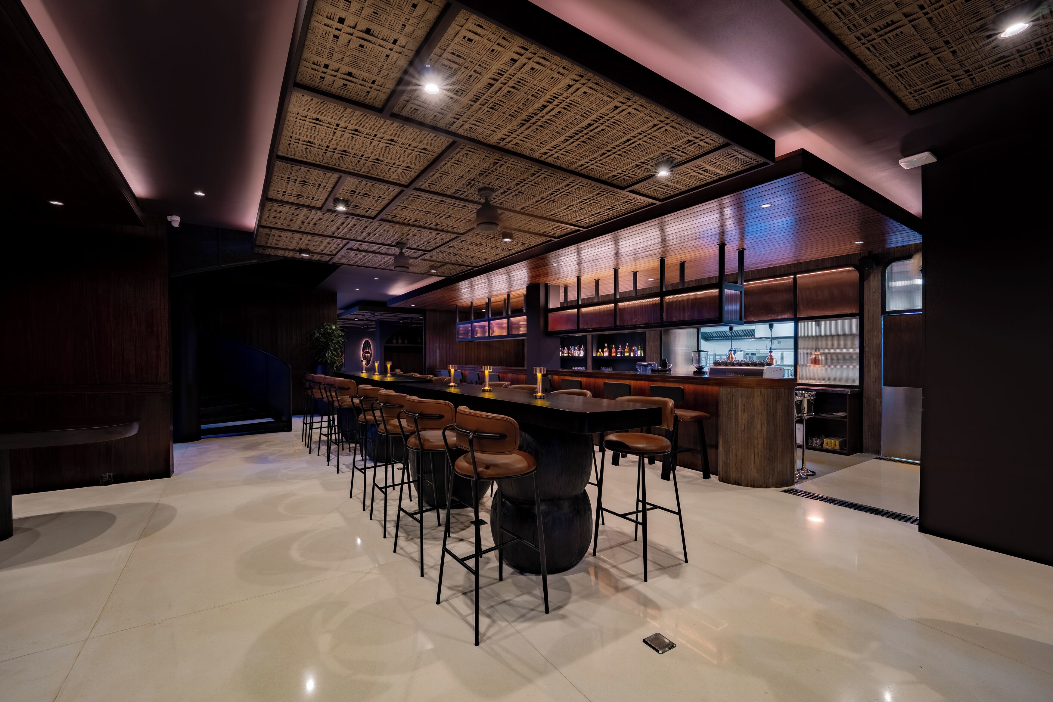 A modern bar area with a high ceiling, bar stools, and a bar counter.