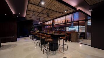 A modern bar area with a high ceiling, bar stools, and a bar counter.
