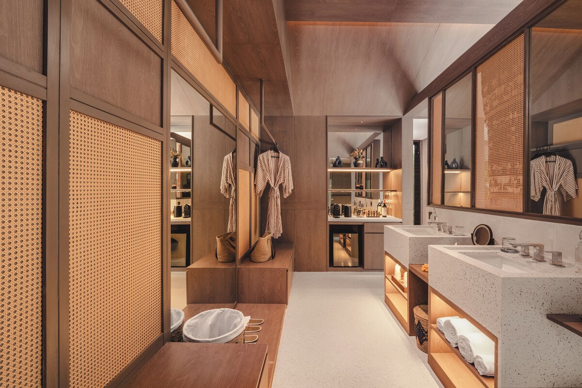 A modern bathroom with a large mirror, wooden cabinets, and a white countertop.