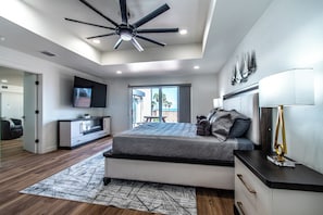 A modern bedroom with a bed, bedside table, and a ceiling fan. - Beachfront Bliss Panoramic Ocean Views Sleeps 33 (Corpus Christi)