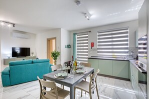 Ein modernes Wohnzimmer mit einer Couch, einem Esstisch, Stühlen und einem Fernseher.
