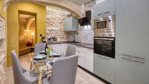 A modern kitchen with stone walls, a dining area with a glass table, and built-in appliances. - Beautiful traditional house in Rabat AMUS1-1 (Rabat)