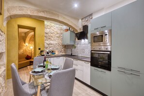 A modern kitchen with stone walls, a dining area with a glass table, and built-in appliances. - Beautiful traditional house in Rabat AMUS1-1 (Rabat)