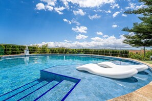 A clear blue swimming pool with a white inflatable float, surrounded by a metal fence and greenery. - Finca with pool Can Pintat in Mallorca (Llubi)
