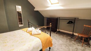 A bedroom with a bed, a chair, a wardrobe, a mirror, and a clothes rack. - The Loft Apartment @ The Stag Inn (Maryport)