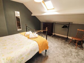 A bedroom with a bed, a chair, a wardrobe, a mirror, and a clothes rack. - The Loft Apartment @ The Stag Inn (Maryport)