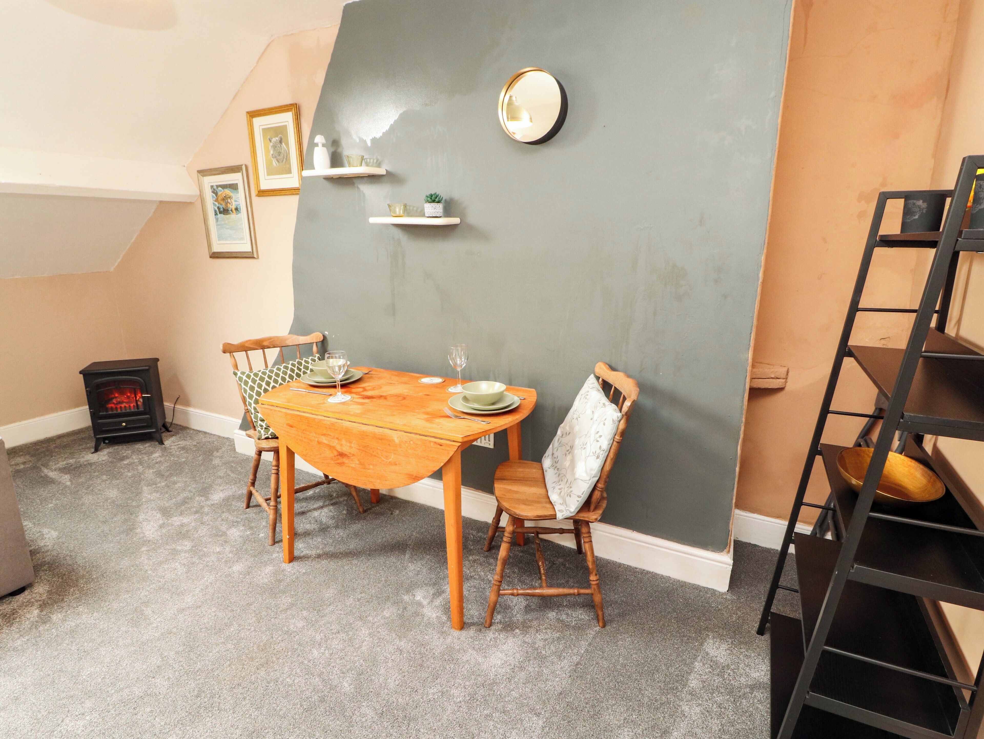Un comedor con una mesa de madera, sillas, una pequeña estufa y una pared de acento gris.