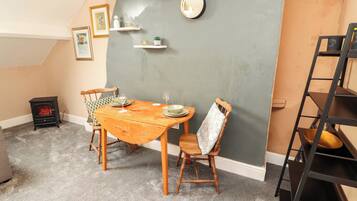 Un comedor con una mesa de madera, sillas, una pequeña estufa y una pared de acento gris.