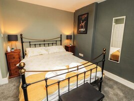 A neatly made bed with a metal frame, a bedside table with a lamp, and a wall-mounted picture.