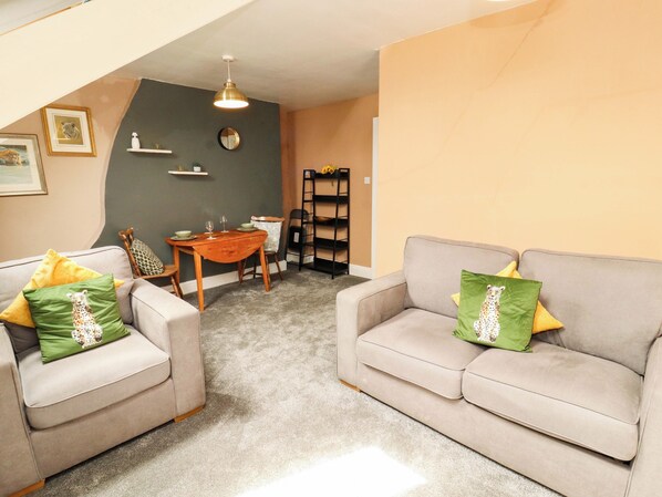 A living room with two sofas, a dining table, and a bookshelf.