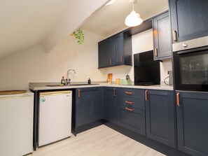 A kitchen with dark cabinets, a white refrigerator, a microwave, and a stove.