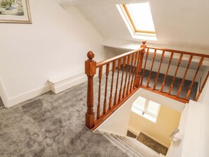 Eine Treppe mit Holzbalustern, Teppichstufen, einem Oberlicht und einem Gemälde an der Wand.