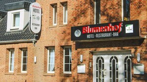 Un edificio de ladrillo con un letrero que dice 'Blumenhof HOTEL RESTAURANT BAR' y otro letrero más pequeño que dice 'Blumenhof HOTEL RESTAURANT BAR'.