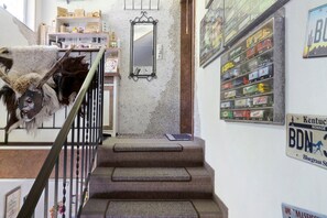 A staircase with a welcome mat, a mirror, and a wall with toy trucks.