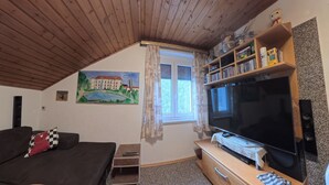 Een gezellige kamer met een televisie, een boekenkast en een schilderij van een gebouw.