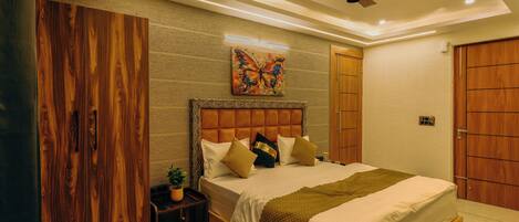 A bedroom with a bed, a ceiling fan, a wall-mounted painting, and a wooden wardrobe.