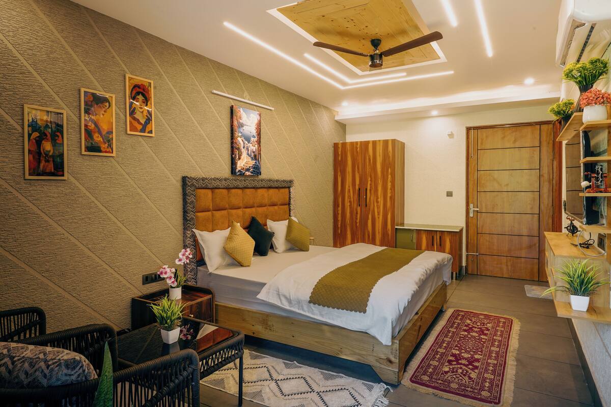 A bedroom with a bed, a nightstand, a chair, a wooden wardrobe, and a ceiling fan.