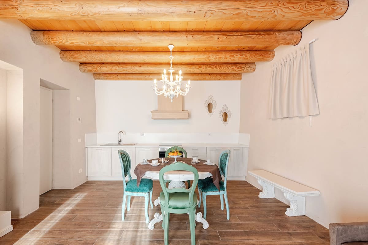 A dining area with a wooden ceiling, a chandelier, a white bench, and a table set for four.