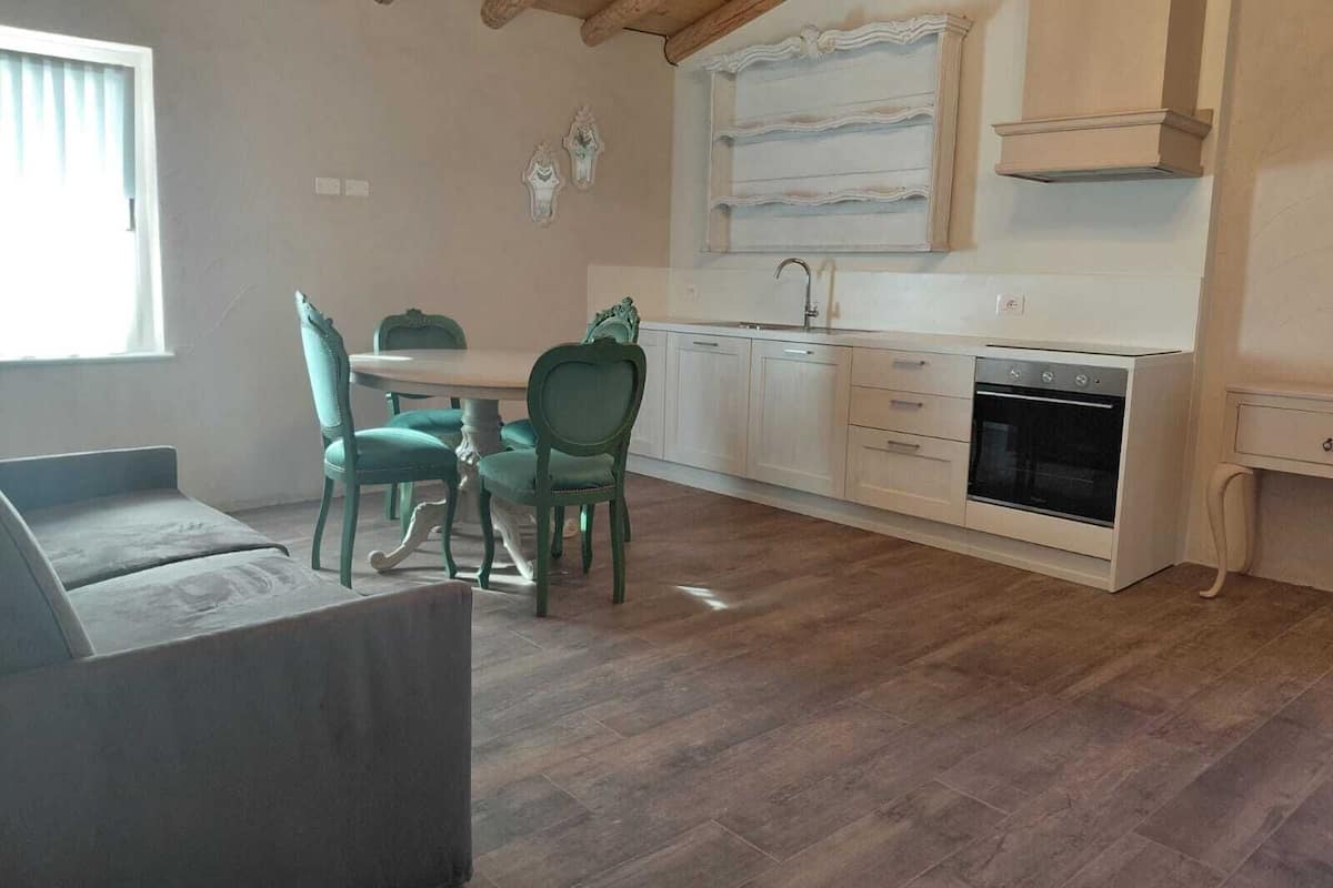 A compact kitchen with a dining area, wooden ceiling beams, and a built-in oven.