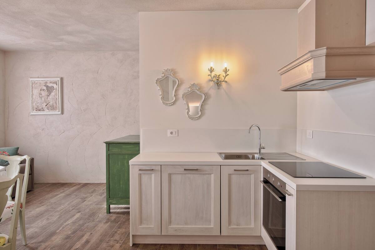 A modern kitchen with a built-in oven, a sink, and a green cabinet.