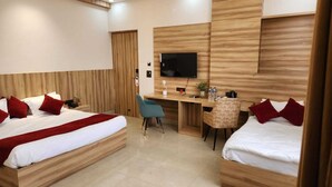 A hotel room with two beds, a desk, a chair, a TV, and a wooden wall panel. - Patram Haveli (Roorkee)