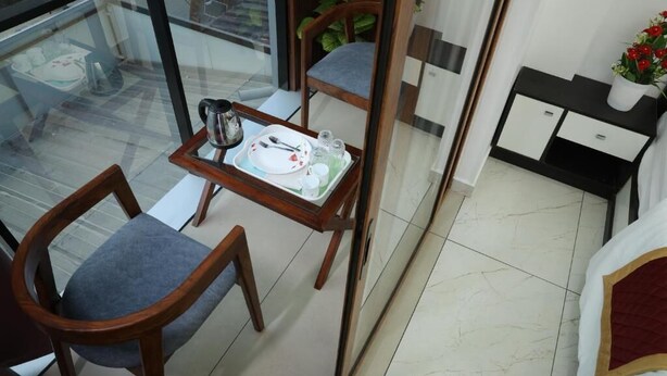 A dining area with a table set for two, a coffee pot, and a tray with cutlery and glasses. - The Avis Resort and Homestay (Idukki)