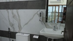 A bathroom with a toilet, sink, and mirror. - The Avis Resort and Homestay (Idukki)