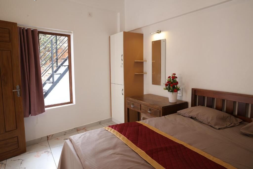 Un dormitorio con cama, armario, espejo, mesita de noche y ventana con vista a una escalera.