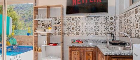 Een moderne keuken met een ingebouwde televisie, uitzicht op een zwembad en een houten kast.