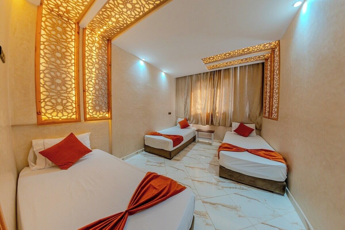 Ein Hotelzimmer mit drei Betten, einer Couch, einer Wandverkleidung und einem großen Spiegel.