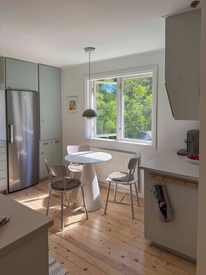 Una cocina moderna con comedor, un ventanal con vistas a árboles y un horno empotrado.