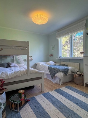 Un dormitorio con literas, una ventana con vistas, un radiador y un pequeño coche de juguete de madera.