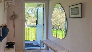 A room with a wooden bench, a wicker basket, a door leading outside, and a framed picture on the wall.