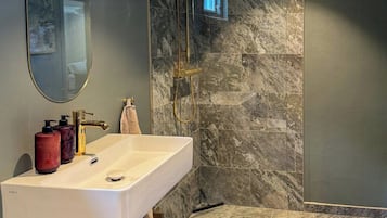 Une salle de bain moderne avec un grand lavabo, un miroir et une douche.
