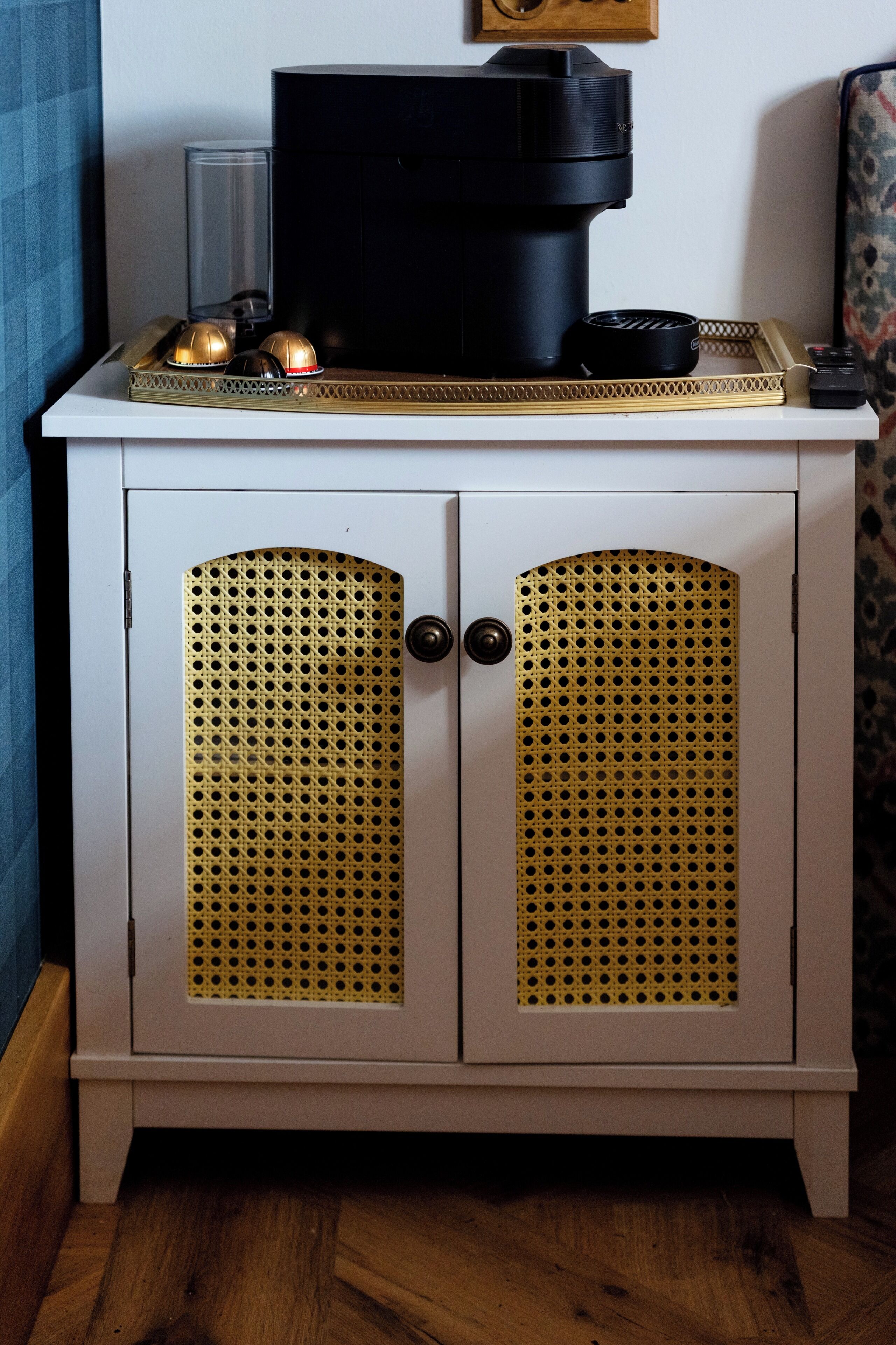 A white cabinet with perforated doors and a black appliance on top.