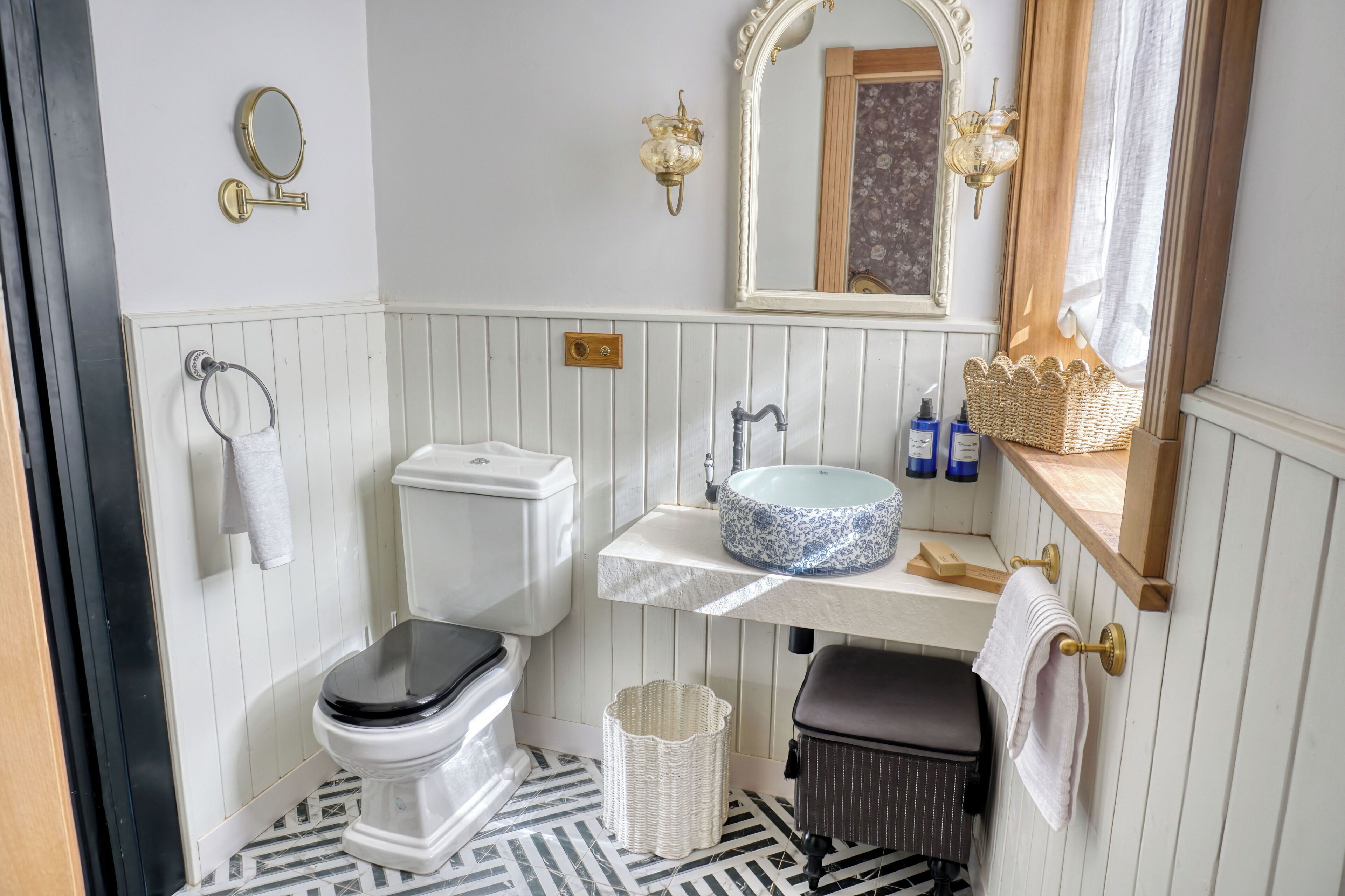 A bathroom with a toilet, sink, mirror, and a trash bin.