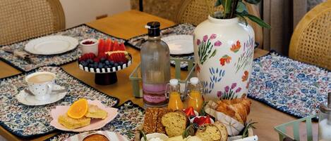A dining table with a floral vase, a fruit platter, and various food items.