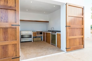 A kitchen with wooden cabinets, a stove, a dishwasher, and a sink. - WHITE OASIS Ibiza Villa (Sant Llorenc de Balafia)