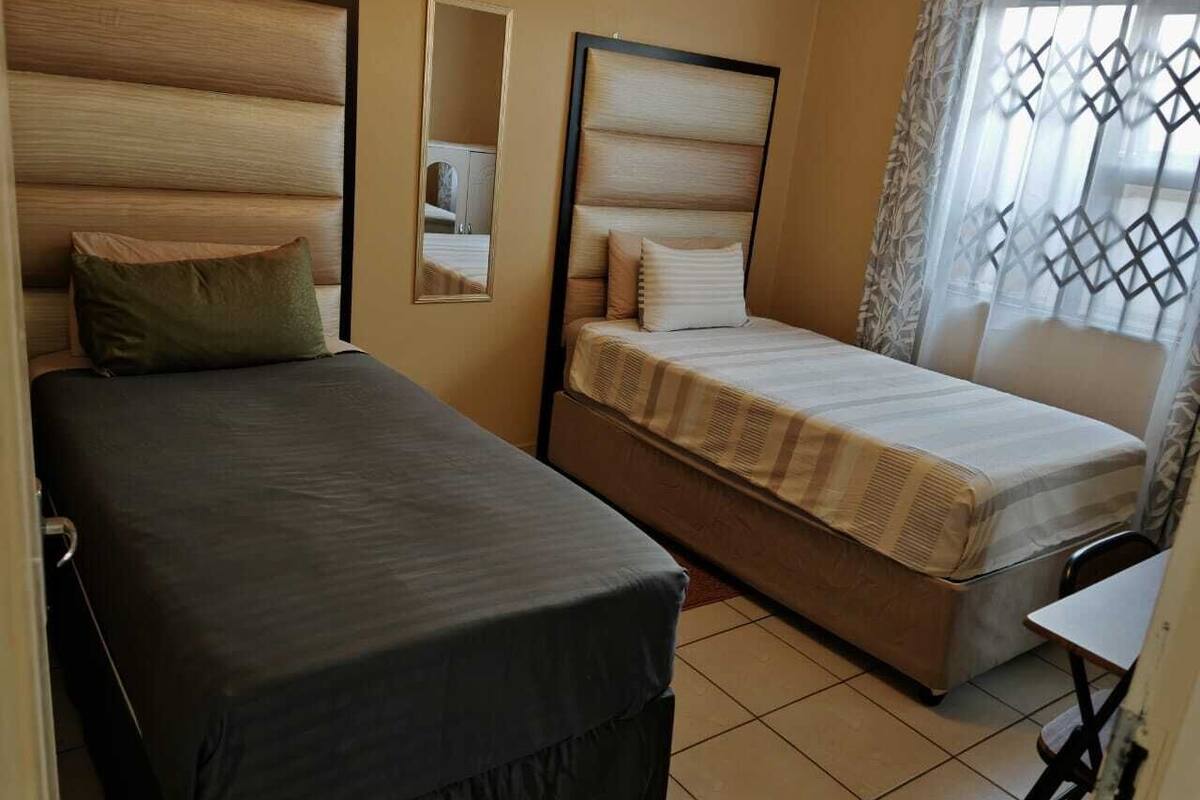 A room with two beds, a small table, and a mirror.