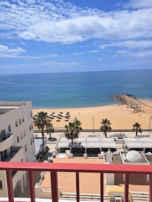 Blick auf einen Strand mit einem Gebäude im Vordergrund, feinem Sand und dem Meer.