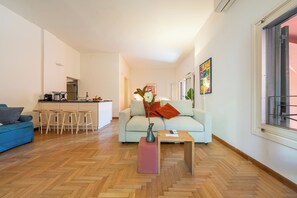 Ein modernes Wohnzimmer mit einer Couch, einem Couchtisch und einer Küche im Hintergrund.