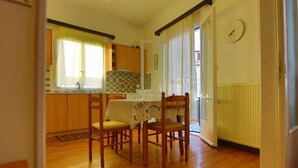 Eine Küche mit Holzausstattung, einem Esstisch mit Stühlen und einem Fenster mit Vorhängen.