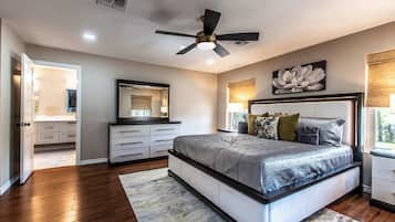 A bedroom with a bed, a ceiling fan, a nightstand, a lamp, and a window.