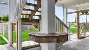 A covered outdoor area with a wooden bench, a staircase, and a view of a fenced yard. - Ocean Views Hear The Waves Sleeps 8 Walk to Beach (Bolivar Peninsula)