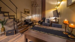 Una sala de estar moderna con una escalera de madera, una mesa de comedor con sillas y un candelabro.