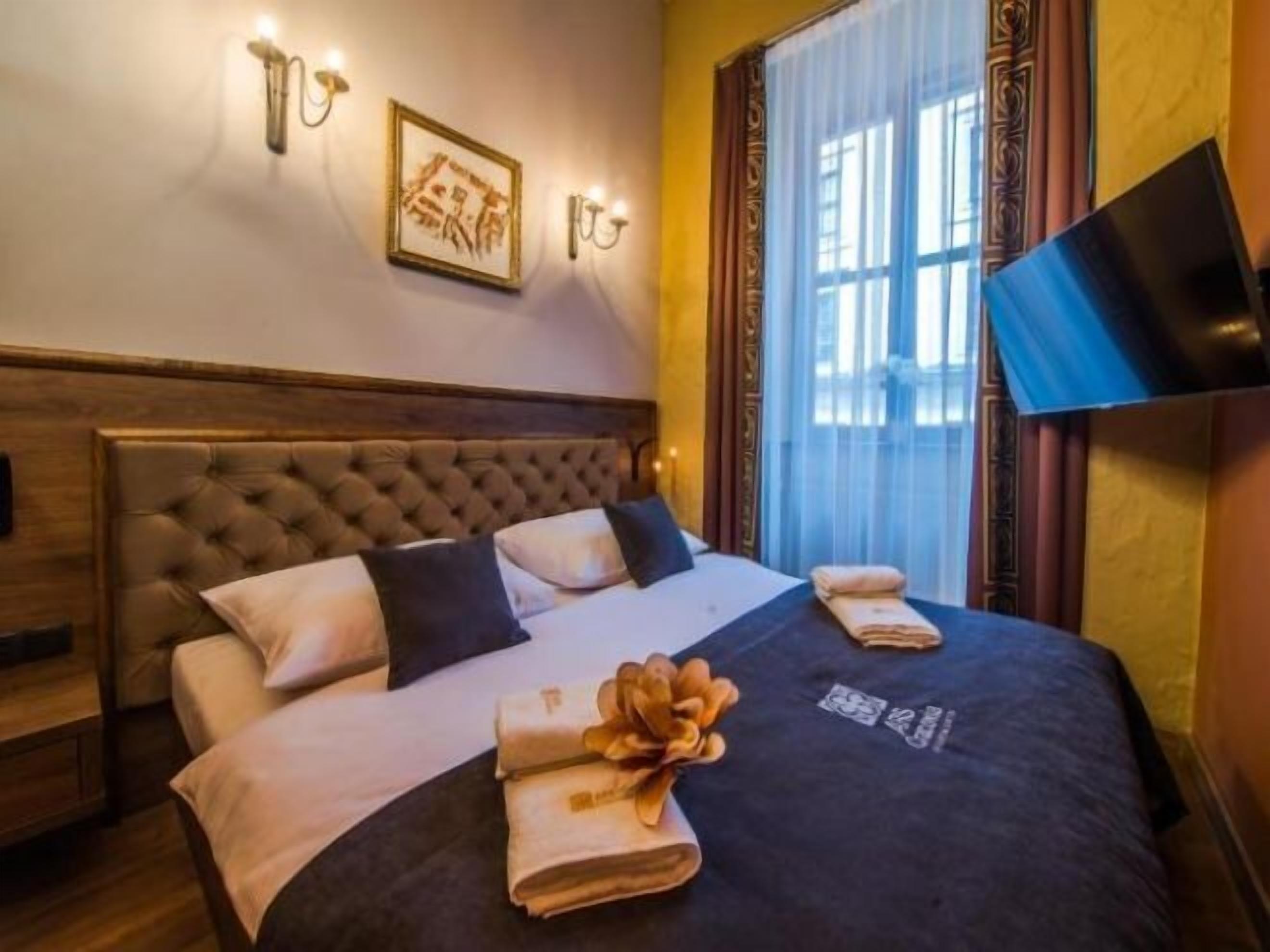 Een hotelkamer met een groot bed, een flatscreen televisie aan de muur en een raam met gordijnen.