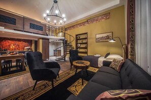 Una sala de estar moderna con un sofá, sillones, una zona de comedor y una escalera que lleva a un nivel superior.