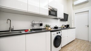 A modern kitchen with white cabinets, a stainless steel sink, a microwave, a built-in oven, a washing machine, and a coffee maker. - Italianway Comfort - Cicco Simonetta 16/a (Milan)